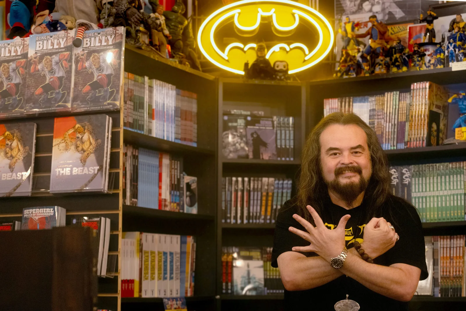 Paul Ortigoni inside Blackbird Comics and Coffeehouse beneath a Batman sign